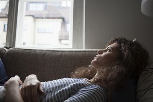 Serious young woman lying on sofa