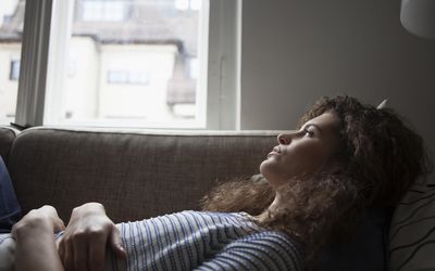 Serious young woman lying on sofa