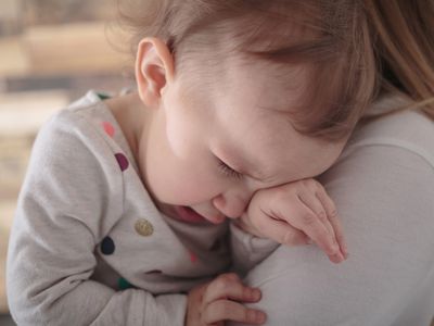 Toddler girl crying on mothers shoulder