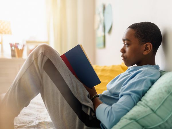 boy reading book on bed