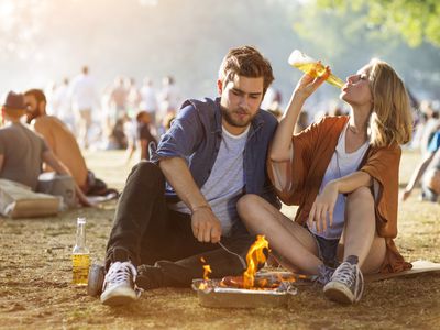 Young couple grilling and drinking beer at outdoor festival