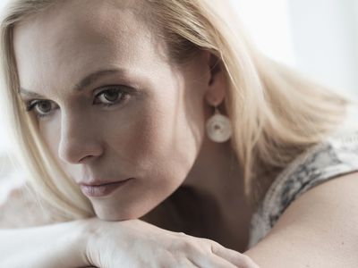 Pensive adult woman lying on bed