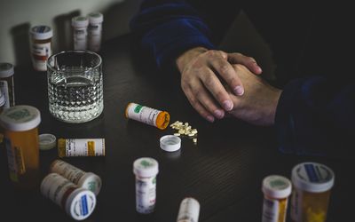 man surrounded by pill bottles