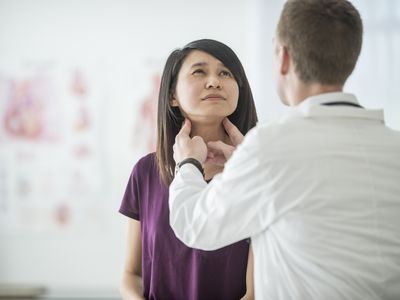 A doctor checking a woman for a thyroid problem.