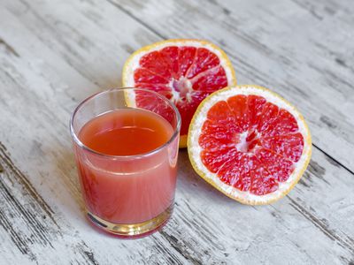 Sliced grapefruit and glass of grapefruit juice on wood