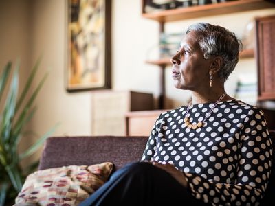 Portrait of woman (60yrs) sitting on couch at home