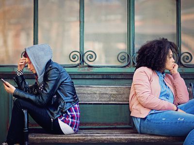 Girlfriends in conflict are sitting on the bench and sulking each other