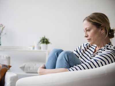 Caucasian woman sitting in armchair holding legs 