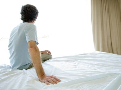 Mature man sitting alone on bed