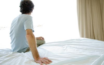 Mature man sitting alone on bed