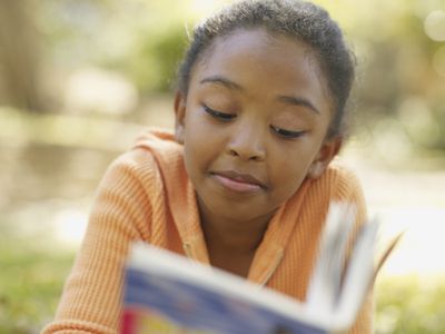 Kid reading a book outside