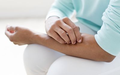 Woman picking skin on arm