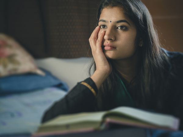 person looking sad while on her bed