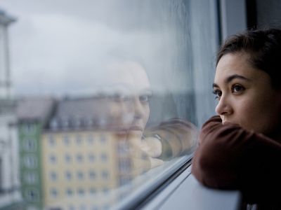 Teenager looking out of window, Munich, Germany