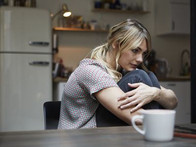 Portrait of pensive woman sitting at table in the kitchen