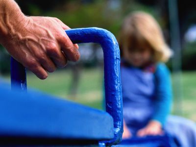 Adult's hand on see-saw, girl (3-5) sitting on opposite seat