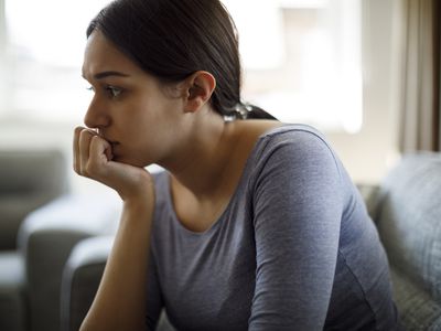 Upset woman sitting on sofa alone at home