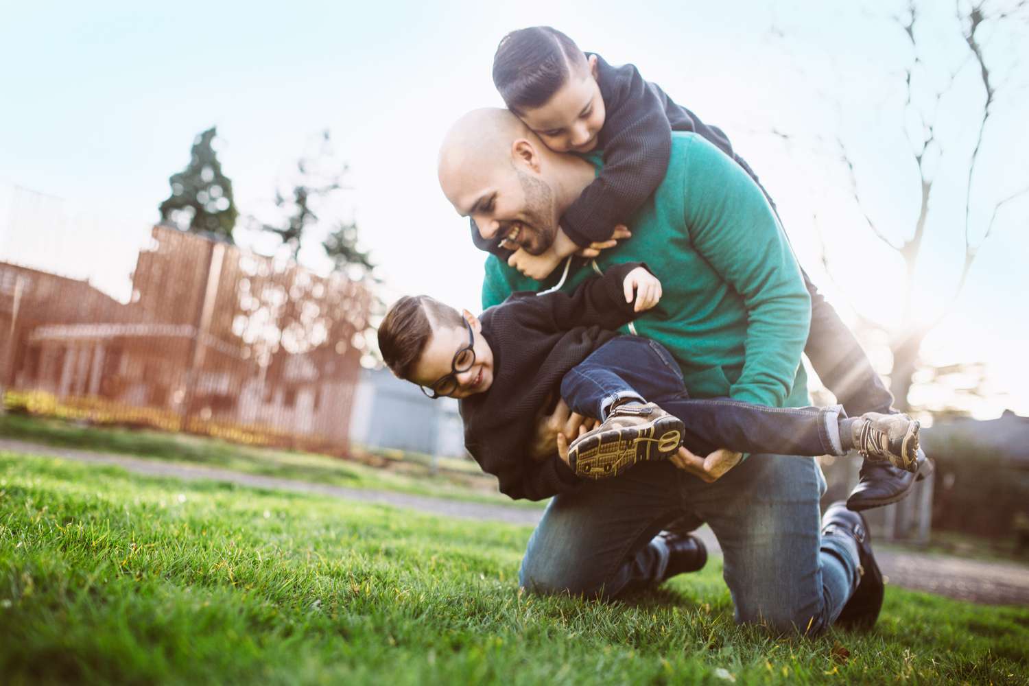 Dad wrestling with his two young sons outside