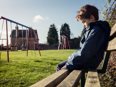 Lonely child sitting on play park playground bench