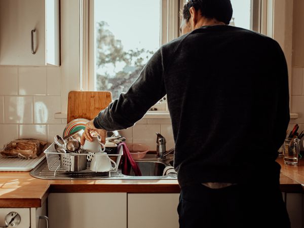 man with back to the camera is doing dishes