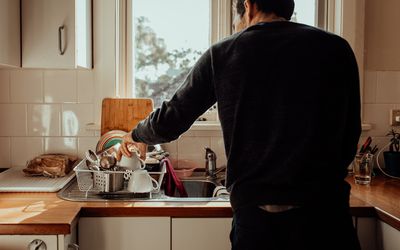 man with back to the camera is doing dishes