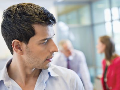 Male executive listening to his colleagues' conversation in an office