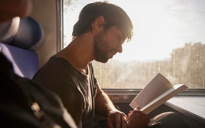 man reading book on train