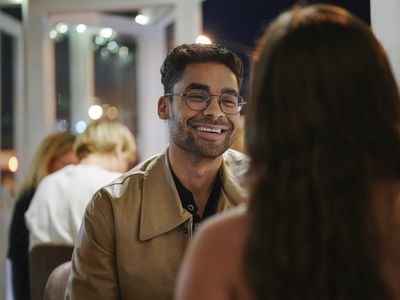 Young man talking and laughing with a young woman while sitting at a restaurant table during a dinner date