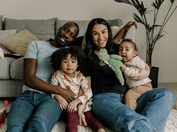 Young family sitting on the floor of their living room smiling for a photo