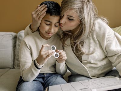 mother kissing son on the forehead, little boy is holding a fidget spinner