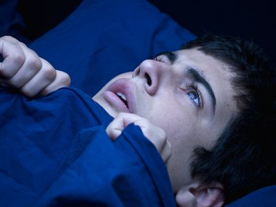 man in bed with blankets pulled up to his chin