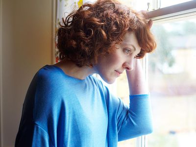 Girl looking out of window of house in suburban street