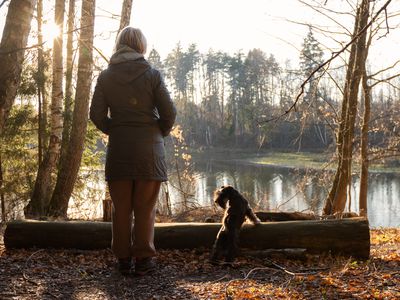 Woman standing overlooking a lake with her dog