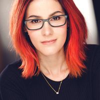 A woman with red hair and black glasses. 