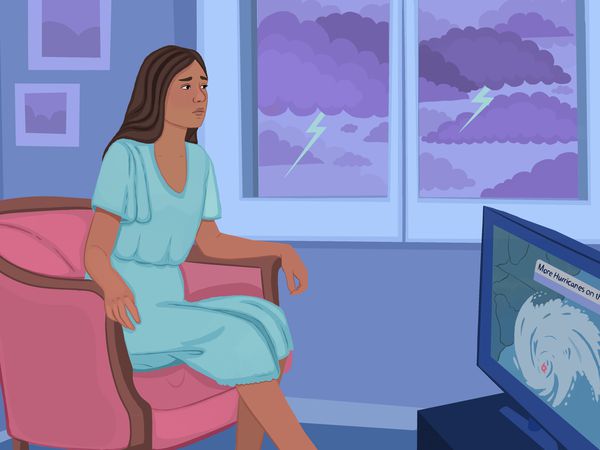 Woman sitting in house and watching the news as hurricane approaches