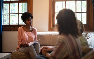 Therapist asking questions to a parent and child and taking notes