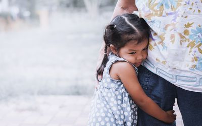 Shy little girl hugging parent's leg