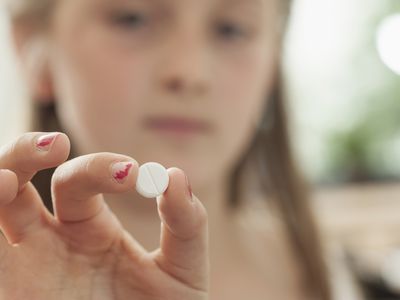 Schoolgirl showing a pill in classroom, Munich, Bavaria, Germany