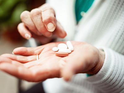 Senior woman holding pills in hand