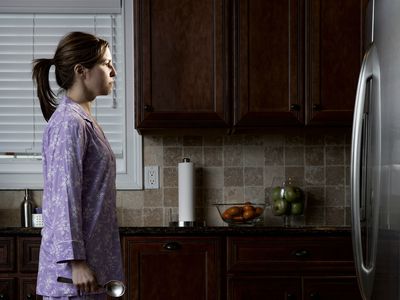 Woman in pyjamas, looking at refrigerator