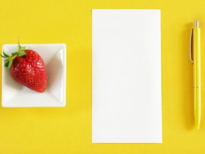 Top view of table with blank paper, strawberry and pen