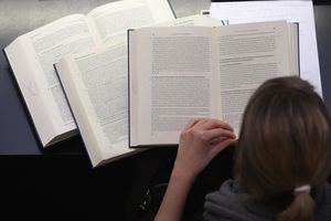 Woman reading from several books open in front of her