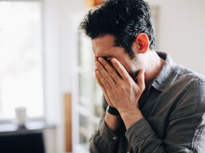 A middle-aged man holds his hands in front of his face, clearly upset