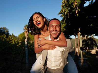 Happy groom piggybacking bride in vineyard