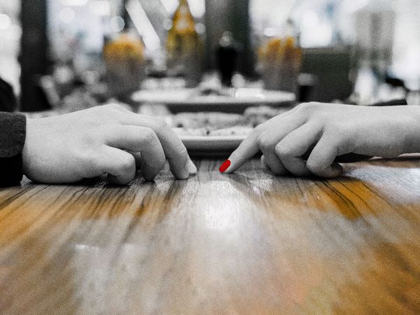 Hands on a table with a red nail