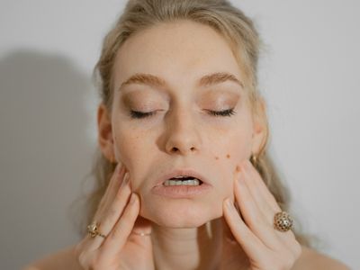 Woman doing face yoga exercises for health benefits. She is stretching her cheeks.