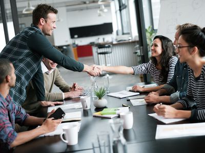 Man shaking hands with a woman surrounded by other people