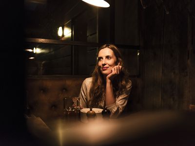 Woman at a dimly lit restaurant resting her head in her hand