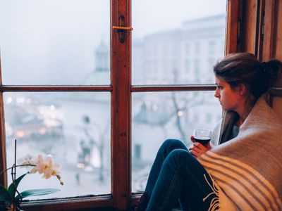 Depressed woman looking out the window in the winter