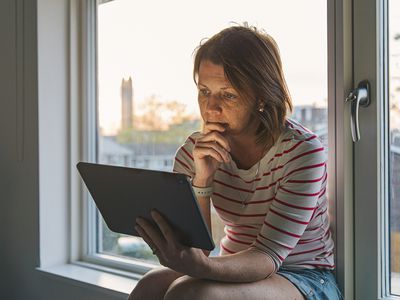 Woman using digital tablet on window sill